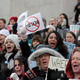 People hold signs at a rally at the Capitol in Olympia, Wash., to oppose a proposed bill that would remove parents’ ability to claim a philosophical exemption to opt their school-age children out of the combined measles, mumps and rubella vaccine.